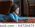 Cute little girl lying down looking at mobile 64726479