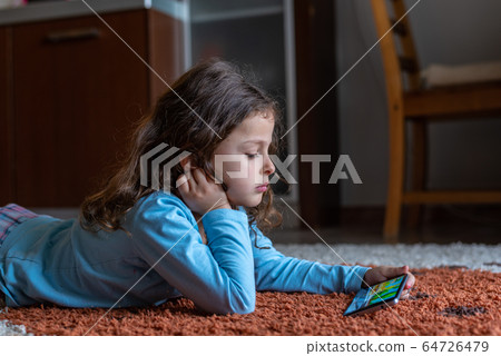 Cute little girl lying down looking at mobile 64726479