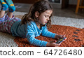 Cute little girl lying down looking at mobile 64726480