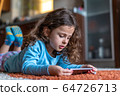 Cute little girl lying down looking at mobile 64726713