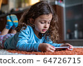 Cute little girl lying down looking at mobile 64726715