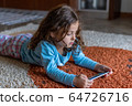 Cute little girl lying down looking at mobile 64726716
