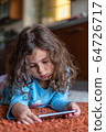 Cute little girl lying down looking at mobile 64726717
