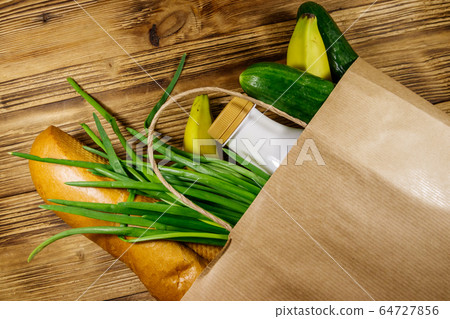 Paper bag with different food on wooden table 64727856