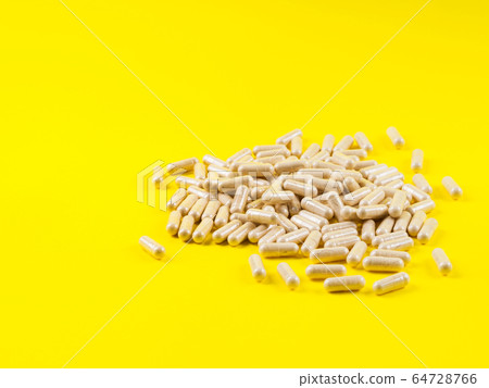 Maca powder in capsules on yellow background Maca powder in capsules on yellow background 64728766