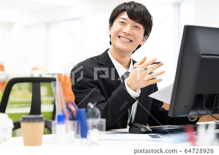 Smiling young male employee in office 64728926