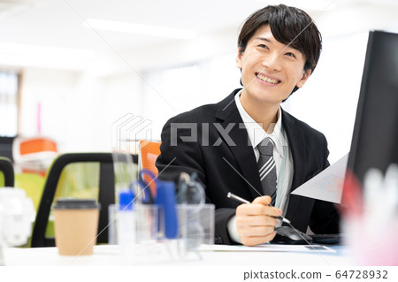 Smiling young male employee in office 64728932