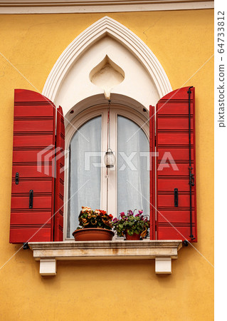 Window with arch and red shutters - Caorle Venezia Italy 64733812