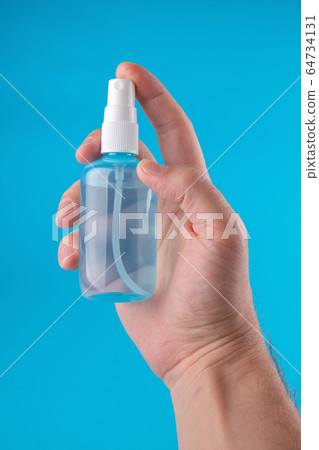 Sanitizer bottle in the male hand, blue background 64734131