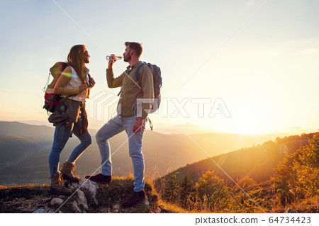 Young Couple Hiking On The Peak of Mountain drinking water 64734423