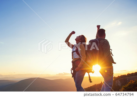 Couple on Top of a Mountain Shaking Raised Hands 64734794