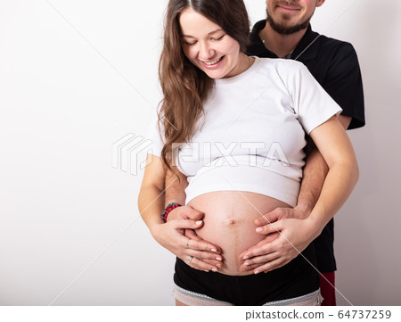Cropped image of beautiful pregnant woman and her handsome husband hugging the tummy 64737259