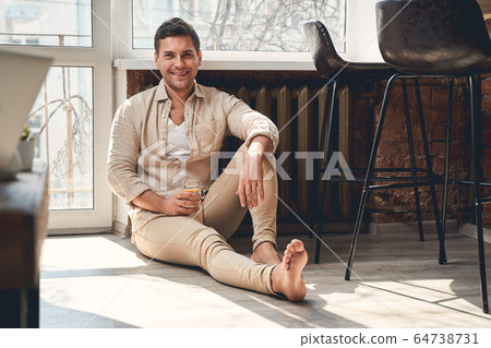 Pleased man holding a glass of lemon water 64738731