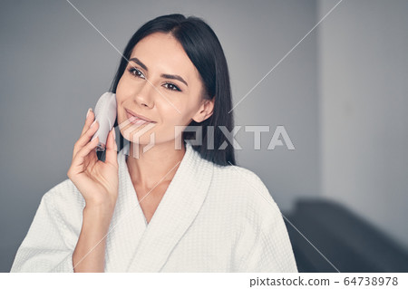 Smiling beautiful girl performing an exfoliation procedure Smiling beautiful girl performing an exfoliation procedure 64738978