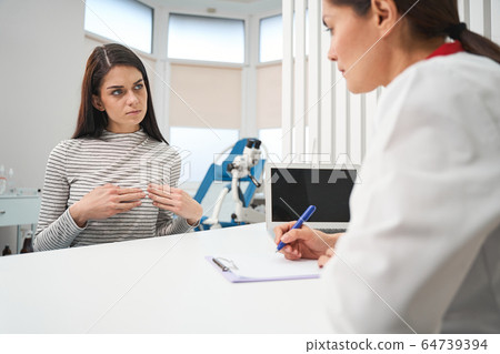 Concentrated practitioner making notes during health examination Concentrated practitioner making notes during health examination 64739394