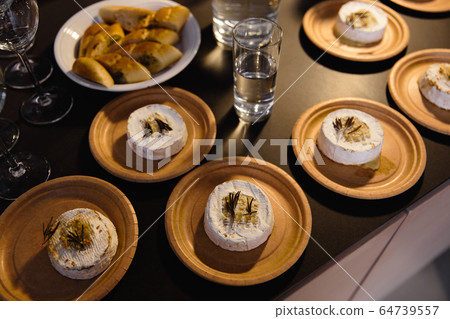 Many delicious hot baked camemberts with sultanas and rosemary on a table Many delicious hot baked camemberts with sultanas and rosemary on a table 64739557