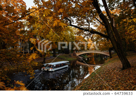 Golden autumn canal with a boat in the centre of Riga, Latvia Golden autumn canal with a boat in the centre of Riga, Latvia 64739633