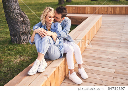 Woman and her Caucasian boyfriend sitting outdoors Woman and her Caucasian boyfriend sitting outdoors 64739897