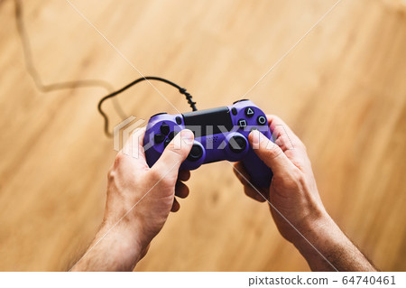 A man is sitting on the sofa and playing a video game. 64740461