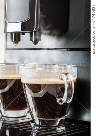 two glass cups of hot espresso are being prepared two glass cups of hot espresso are being prepared 64740889