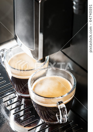 glass cups of hot espresso are being prepared in the coffee machine glass cups of hot espresso are being prepared in the coffee machine 64740891