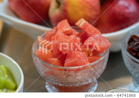Slicing grapefruit on a table in a bowl. Against the background of other fruits Slicing grapefruit on a table in a bowl. Against the background of other fruits 64741868