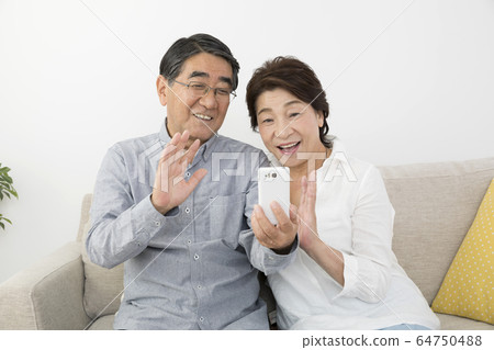 年長的夫婦拒絕出去在智能手機上撥打視頻電話 年長的夫婦拒絕出去在智能手機上撥打視頻電話 64750488