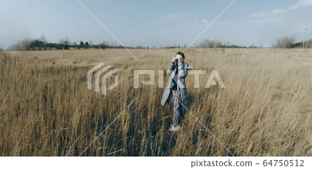 Woman taking photo on yellow field. 64750512