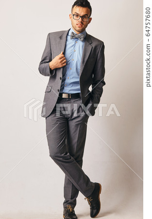 Full length portrait of a young businessman standing with his hands in the pockets. Full length portrait of a young businessman standing with his hands in the pockets. 64757680