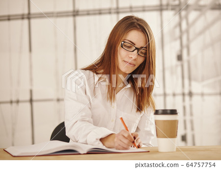 Portrait of businesswoman writes a document at her office. Portrait of businesswoman writes a document at her office. 64757754