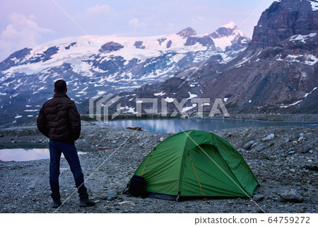 Man enjoying mountains scenery near tent. 64759272