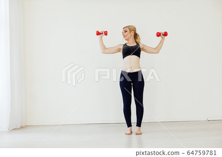 Beautiful blonde woman sports with fitness dumbbells in the hall Beautiful blonde woman sports with fitness dumbbells in the hall 64759781