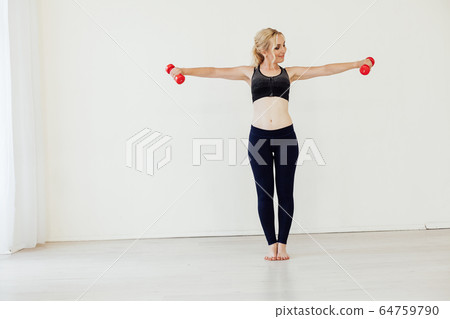 Beautiful blonde woman sports with fitness dumbbells in the hall Beautiful blonde woman sports with fitness dumbbells in the hall 64759790