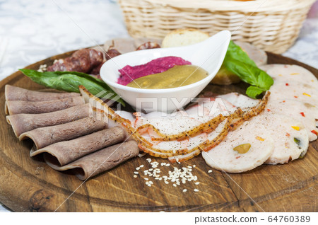 Wooden plate with several types of sausage and bacon sauce. 64760389