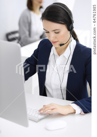 Call center. Beautiful woman sitting and working in headset at customer service office. Business concept 64761985