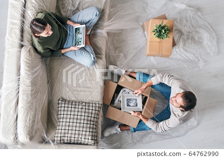 Top view of young woman with tablet chatting to husband with picture in frame Top view of young woman with tablet chatting to husband with picture in frame 64762990