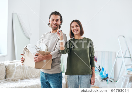 Happy young husband and wife with toothy smiles standing in front of camera 64763054