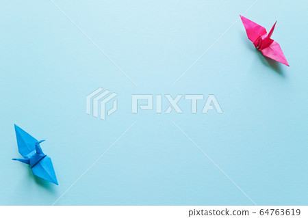 Image of physical distance consisting of two blue and red paper cranes on a blue background 64763619