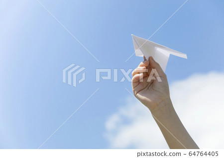 Hand of a child flying a paper airplane 64764405