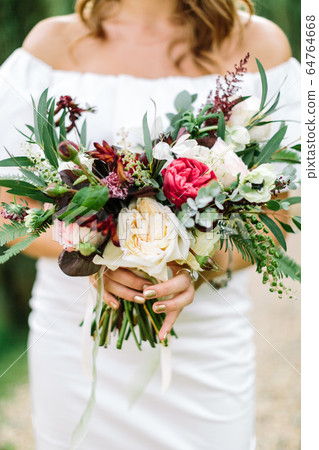Close-up bouquet of flowers in women's hands. style, floral arranging, wedding concept.  64764668