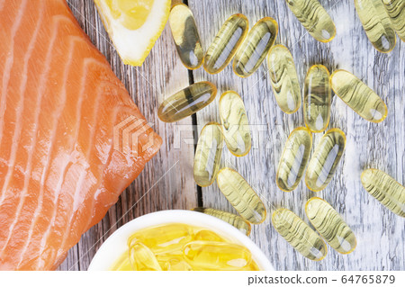 Handful of omega 3 softgels and salmon filet Handful of omega 3 softgels and salmon filet 64765879