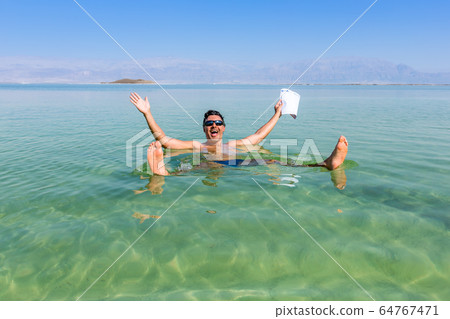 Man with open arms. Dead Sea coastline. Salt 64767471