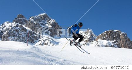 Skier jumping in front of rock mountains Meribel sun snowy mountain landscape France alpes 3 vallees Skier jumping in front of rock mountains Meribel sun snowy mountain landscape France alpes 3 vallees 64771042