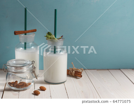 almond plant-based lactose-free milk in glass bottles on a blue background, horizontally with space 64771075