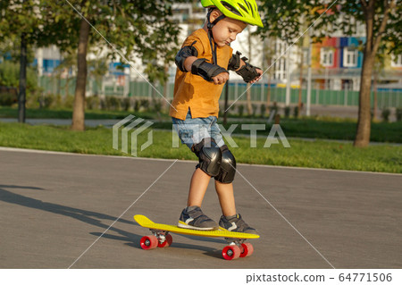 A little boy enjoys a yellow cruiser penny 64771506