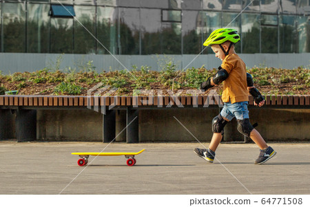 A little boy enjoys a yellow cruiser penny 64771508