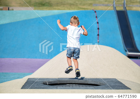 Little boy jumping on trampoline 64771590