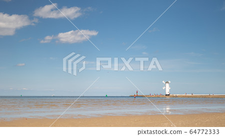 lighthouse and windmill on the seashore 64772333