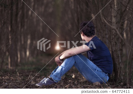 A thoughtful man in the woods looks up to the light in the hope of better times. copy space A thoughtful man in the woods looks up to the light in the hope of better times. copy space 64772411
