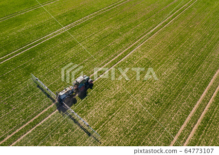 tractor spraying herbicides on field, Tractor Spraying Chemicals on Field - GMO Crops. tractor spraying herbicides on field, Tractor Spraying Chemicals on Field - GMO Crops. 64773107